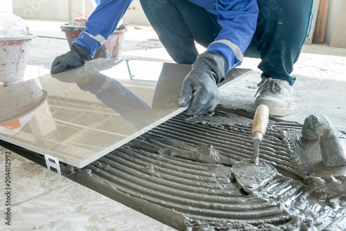 Foto Skilled hands meticulously lay a pristine tile onto a bed of wet cement, a testament to careful craftsmanship and the foundation of a new space