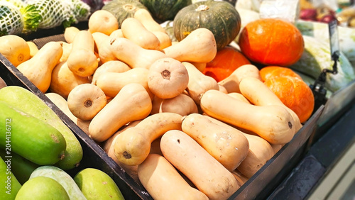 Butternut Squash Harvest: A vibrant display of fresh butternut squash and other gourds, Fresh butternut squash and pumpkins on display at grocery store.