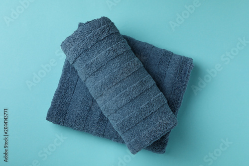 Clean folded towels on blue background, top view
