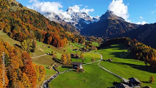 A scenic mountain valley with autumn trees and snow peaks