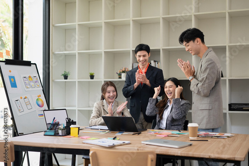 Excited Asian Business Team Celebrating Success in Modern Office Meeting with UX Design Presentation