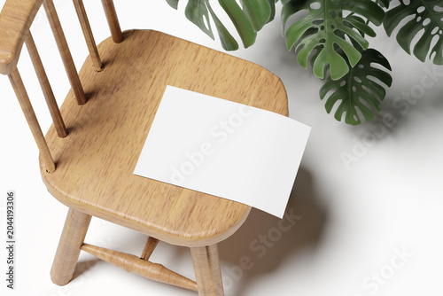 Blank white paper mockup on a wooden chair with monstera deliciosa plant leaf background, minimalist stationery flyer poster card template for branding and portfolio design
