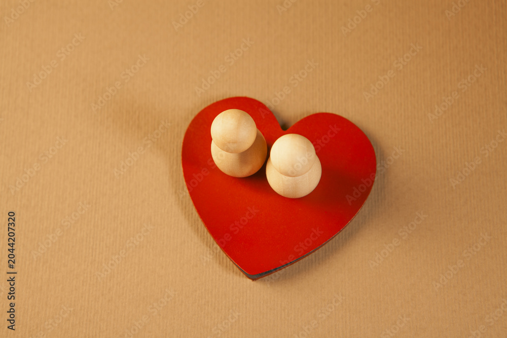 Fototapeta premium Two wooden figures in the form of a heart on a red background