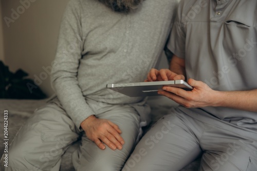 Photography Caregiver assisting elderly man using digital tablet