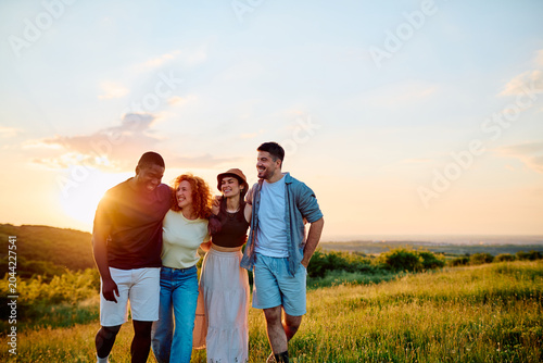 Foto Group of diverse friends walking and smiling in a grassy field, enjoying a beaut