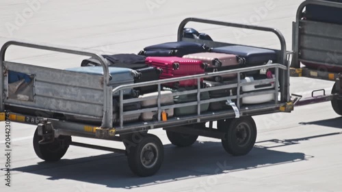 Suitcases on a baggage tractor trolley at the airport. Fast delivery of luggage to the plane, transportation and air travel