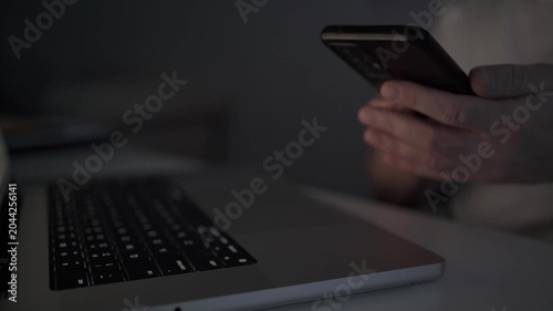Businessman Checking Smartphone While Working on Laptop