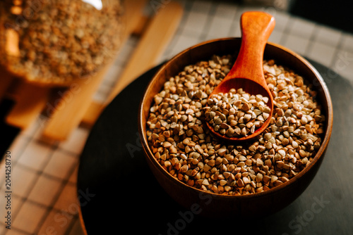 Photos Fresh organic green buckwheat groats in a rustic wooden bowl with a measuring sp
