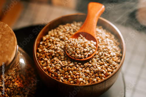 Canvastavla Steaming organic green buckwheat groats in a rustic wooden bowl with spoon