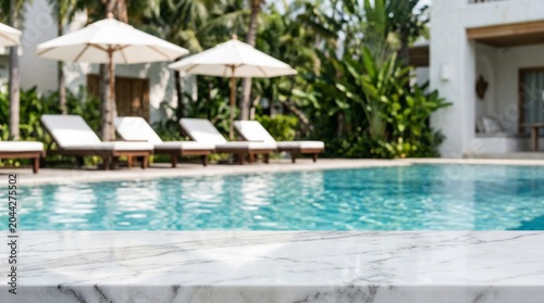 Luxury white marble tabletop foreground with beautiful copy space, featuring a blurred luxury swimming pool background at a tropical resort with lounge chairs, white umbrellas, palm trees, and sunny s