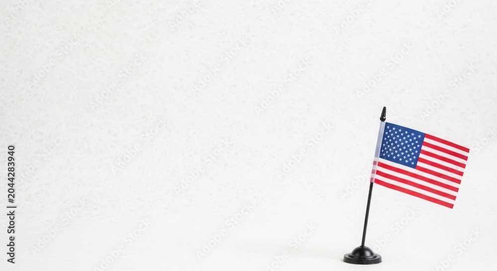 Fototapeta premium Small american flag on black stand against textured white backdrop, representing american values and freedom.