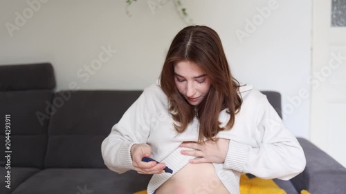 Young woman carefully injects peptide medication into abdomen at home following personal wellness routine focused on recovery health goals and body care