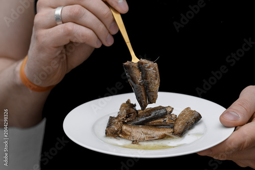 A man eating sardines skewered on a fork.