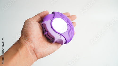 Hand holding medicine dry powder inhaler on grey background. Pharmaceutical product is used to lung inflammation and prevent asthma attack. Asthma and COPD concept.