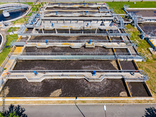 Фотография Workers manage a water treatment facility with multiple tanks and machinery in a