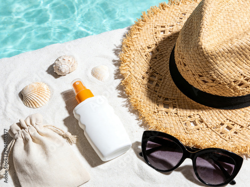 Sun hat, sunglasses and sunscreen on resort beach sand