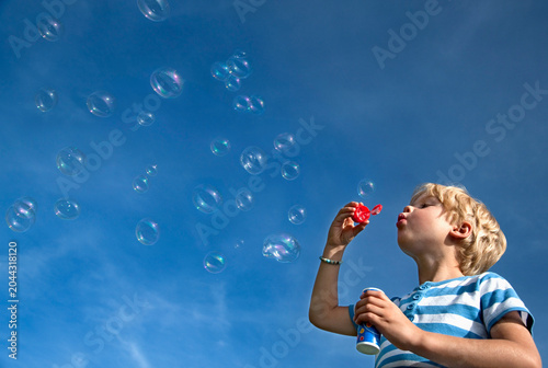 Germany, Bavaria, Boy (4-5 Years) blowing soap bubbles