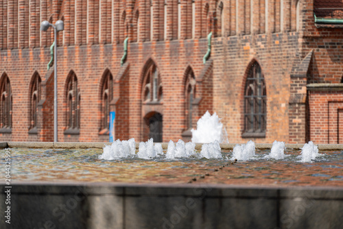 Foto Water jets rise before the red brick Rotes Rathaus facade in Berlin
