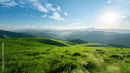 Vibrant green hills and distant mountains under sunny sky