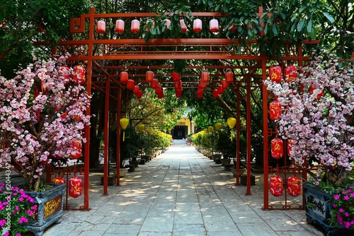 Fotografía Decorative red metal archway alley with hanging lanterns and artificial pink blo
