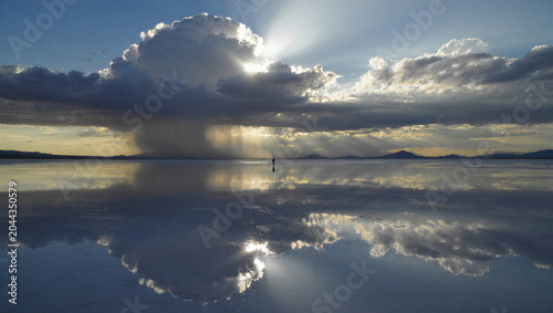 Obraz na płótnie A lone person standing on the vast salar de uyuni salt flats during a dramatic s