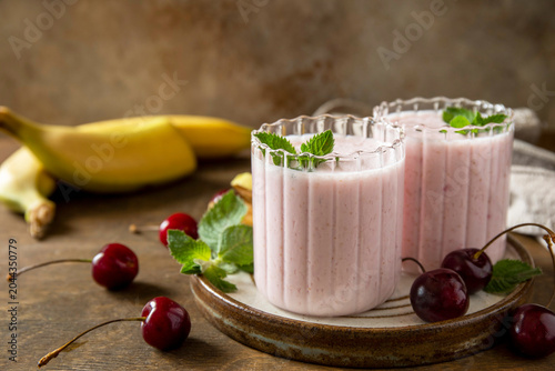 Pink cherries and banana fruit smoothie or milk protein shake on stone tabletop. Yogurt cocktail, natural detox. Liquid ice cream. Copy space.