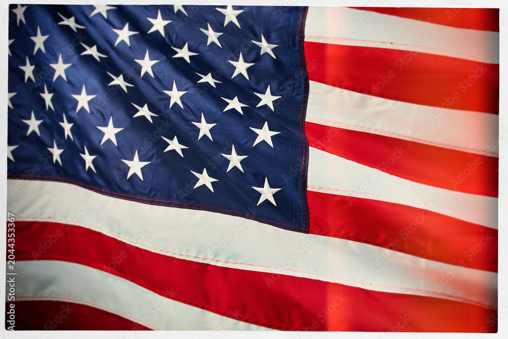 Fototapeta premium Close-up of the American flag in a white frame, featuring stars and stripes in vibrant red, white, and blue colors. Patriotic USA background with detailed fabric texture