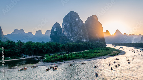 Canvas Print Karst peaks and bamboo forest along Li River at sunset, bamboo rafts sailing on