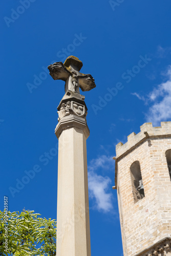 Gothic stone cross monument near a medieval church tower in Spain