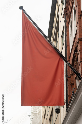 Blank Red Flag Mounted on a Building Facade