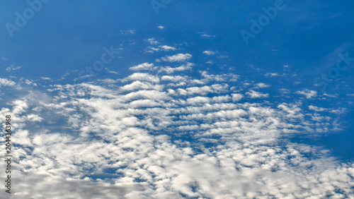 Foto Wavy white altocumulus undulatus clouds arranged in a distinct ripple pattern against a vibrant blue sky during the daytime