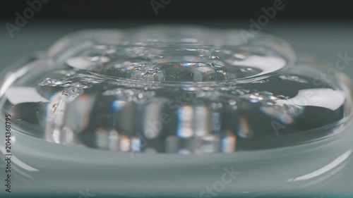 Close-up shot of a clear glass plate with a decorative pattern on a gray surface with a shallow depth of field.