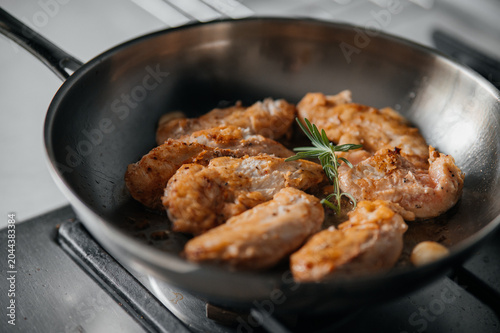 Frying seasoned chicken pieces in a stainless steel skillet