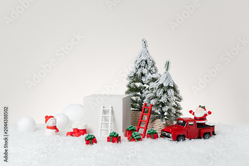 Canvastavla Christmas product display scene featuring snow-covered pine trees, white podium, red little truck, snowman figurine, Santa Claus, wooden ladder prop, and gift boxes arranged on artificial snow