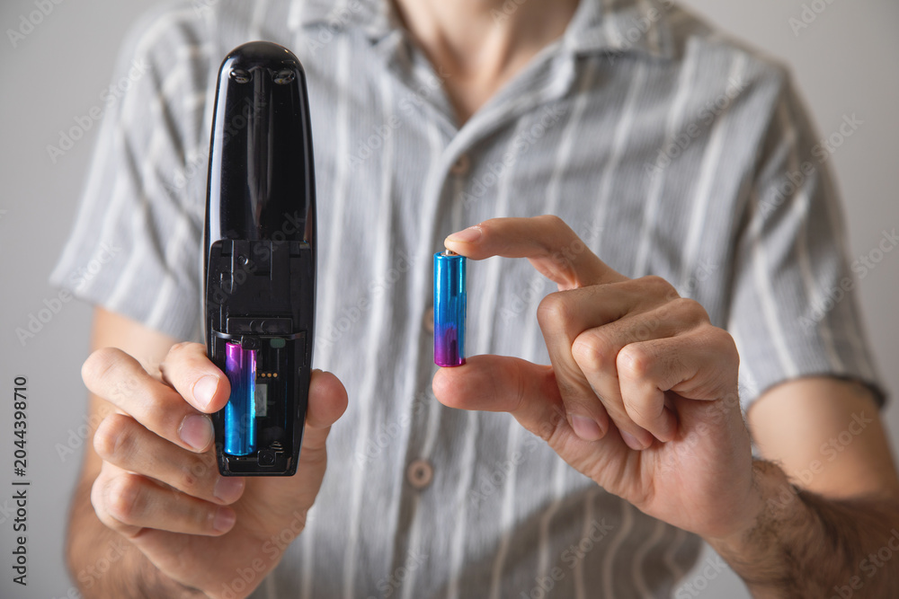 Obraz premium Man installs a new battery in the remote control of a TV.