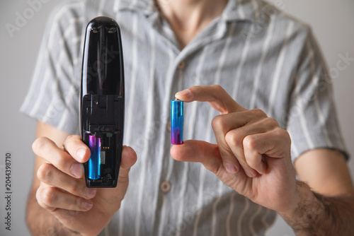 Foto Man installs a new battery in the remote control of a TV.