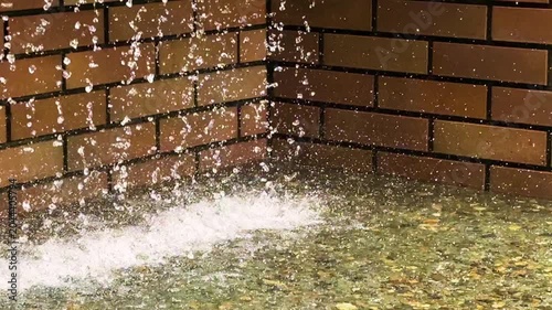 水しぶきや水滴のある流れる噴水　レンガの壁を噴出される水がはじける風景