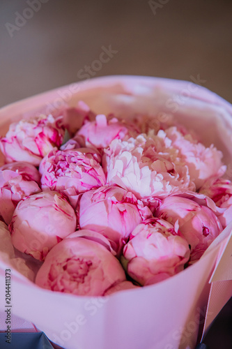 Beautiful bouquet of fresh pink peonies in paper wrapping