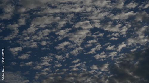 Time-lapse view of small white clouds with shifting light effects in the sky.