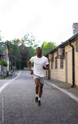Young Black man running through an urban street.