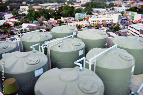 Foto A cluster of large rooftop water storage tanks connected by PVC pipes sits above