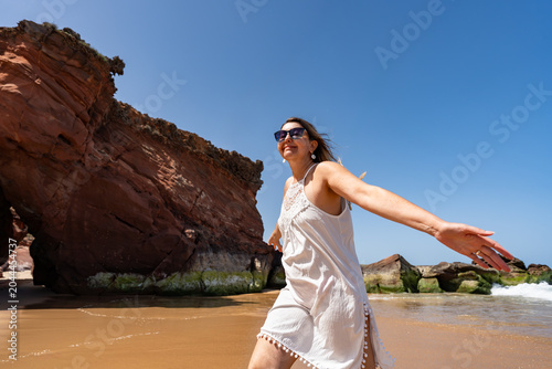 Beautiful middle-aged woman enjoying walk on beach on sunny summer day
