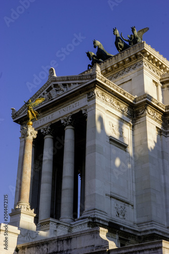 Εκτύπωση καμβά The Altare della Patria, also known as the Monument to Victor Emmanuel II, in Rome, Italy, features a golden statue of Victoria and a quadriga (a chariot drawn by four horses)