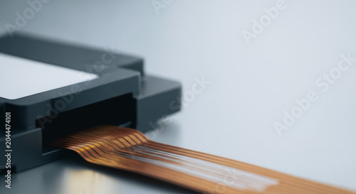Macro View of a Flexible Flat Ribbon Cable Connected to an Electronic Housing Representing Modern Hardware Technology