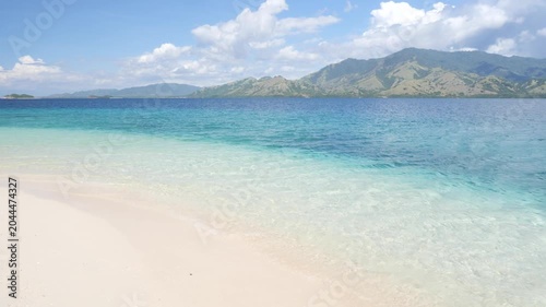 Pristine white sand beach and crystal-clear turquoise waters in Riung 17 Islands Marine Park, Flores, Indonesia, with small tropical islands on the horizon under a bright blue sky