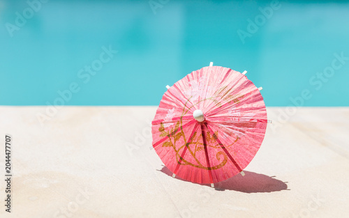 Red paper umbrella on swimming pool edge, summer season background