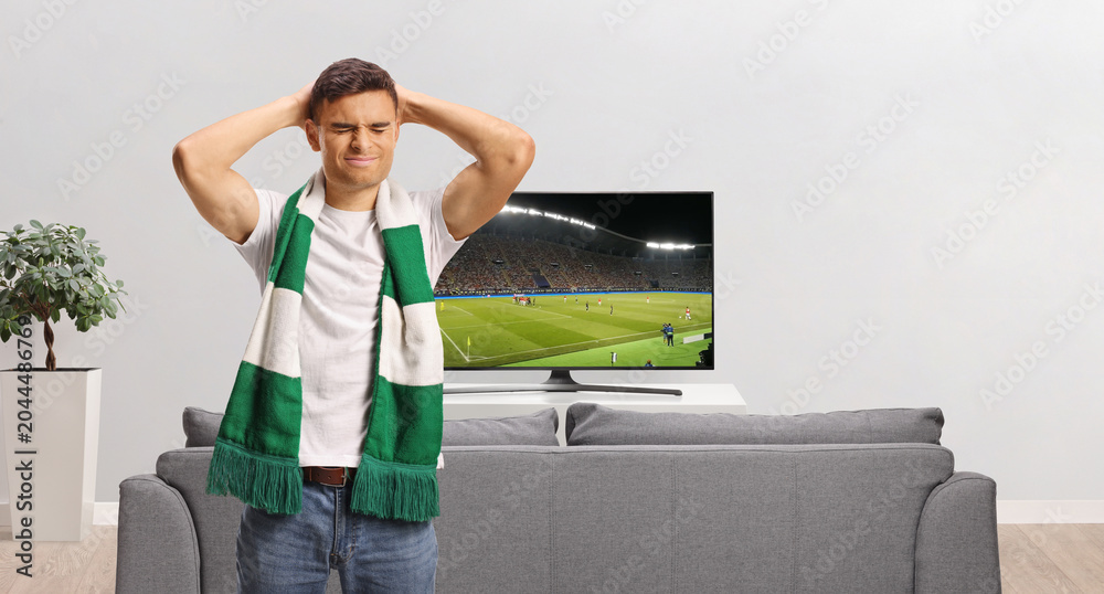 Obraz premium Disappointed man standing in front of a tv