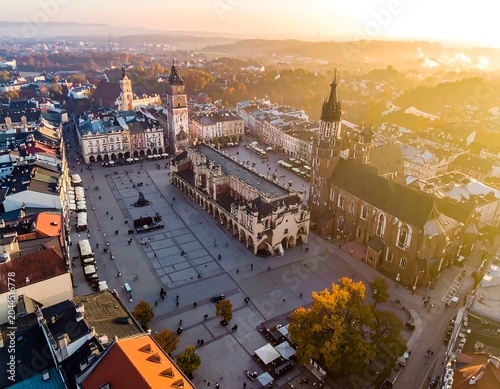Aerial view of a historic town square with buildings and a tower at sunset