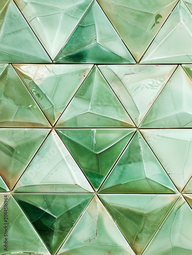 Green triangle tiles form a geometric wall. Unique textures and a modern, artistic design
