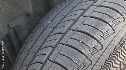 Video footage showing detailed inspection of a vehicle tire tread after locating puncture damage. Automotive service footage focused on tire condition assessment, maintenance procedures, and vehicle s